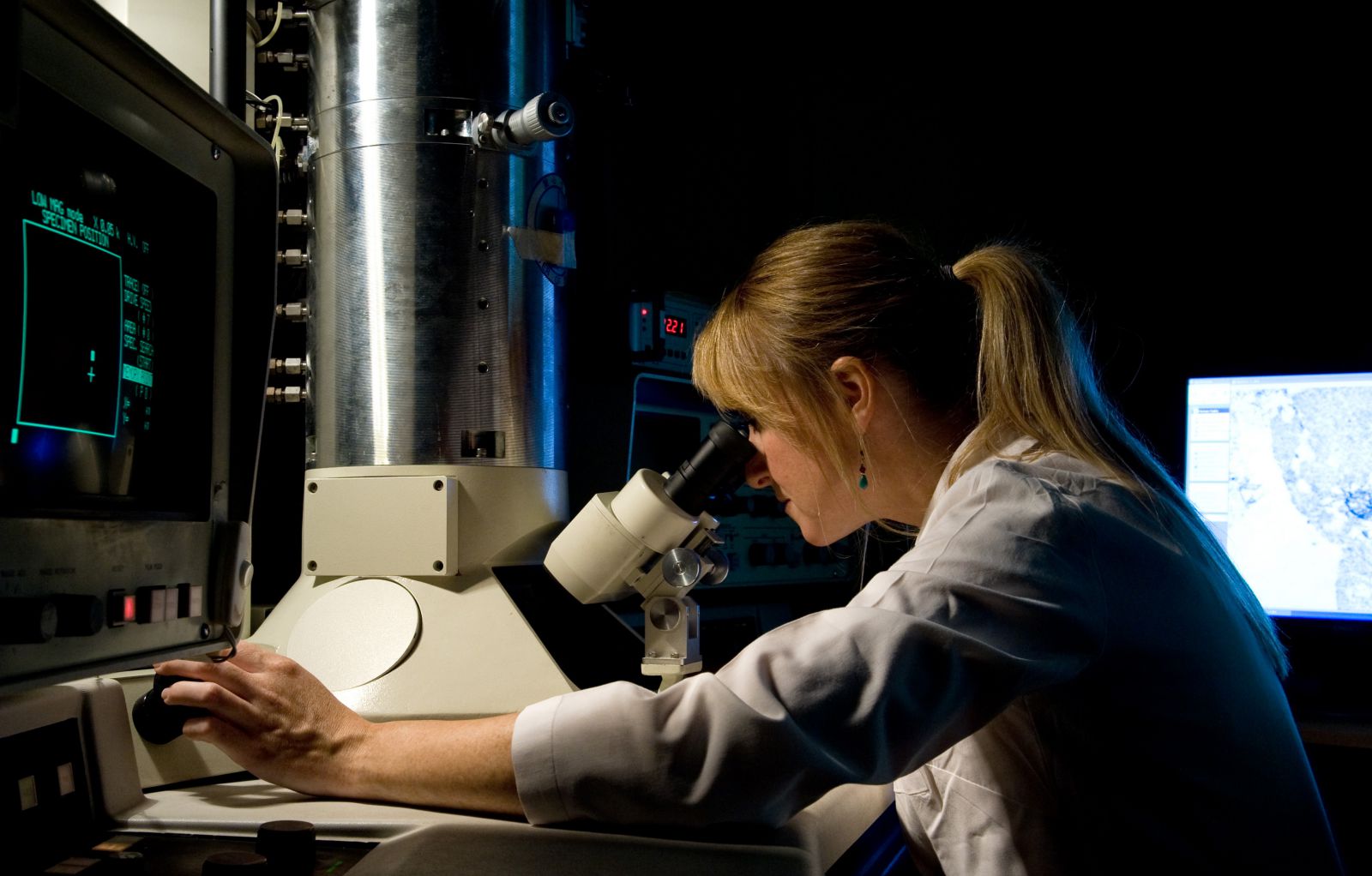 PhD student looks through a microscope in a science lab at the ɫ