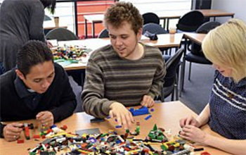 Three people building with lego at the ɫ